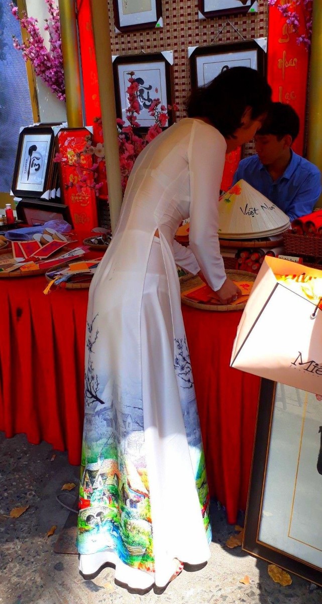 柄の入った白いアオザイを着たベトナム人女性